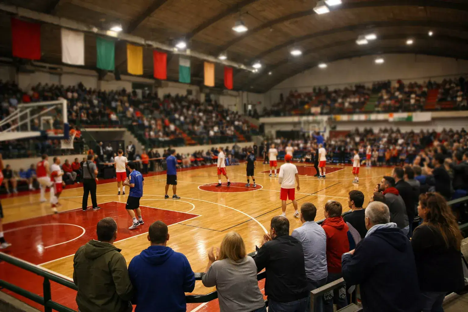 Partita di basket in un piccolo palazzetto italiano con tifosi appassionati vicino al campo